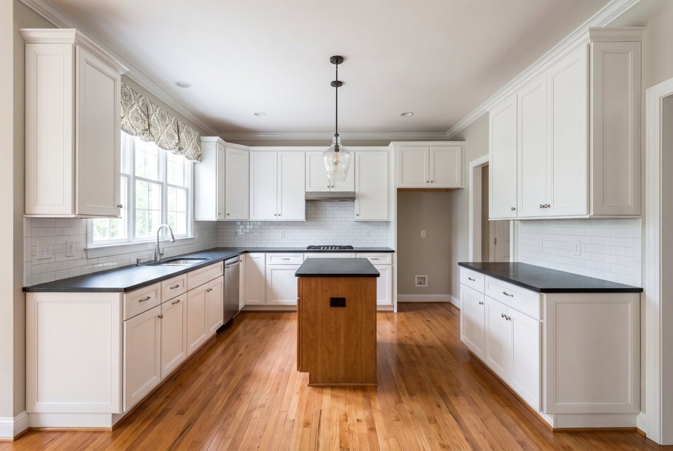 A remodeled kitchen with white cabinets, granite counters and a subway-tile backsplash