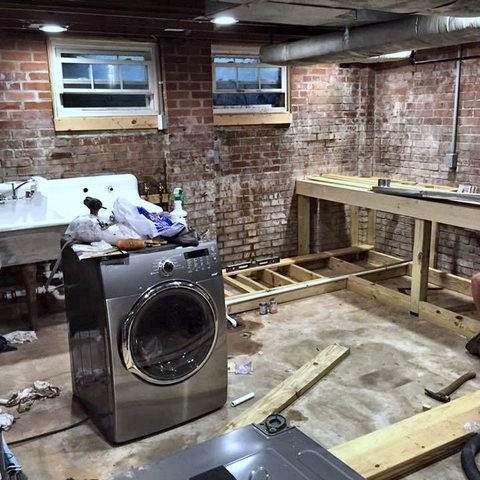 A basement being fitted out with a new counter frame against an exposed brick wall