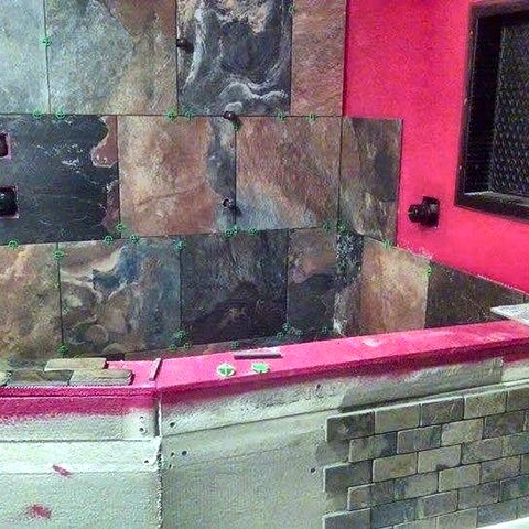 Multi-tone slate tile being set on a shower wall over the waterproofed substrate