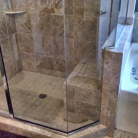 A finished walk-in shower in slate tile with a frameless glass panel