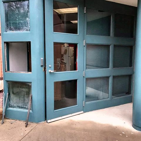 A set of tall commercial glazed doors painted in a deep teal