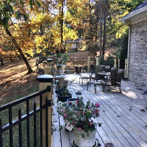 A raised deck with black metal railings, planters and outdoor furniture