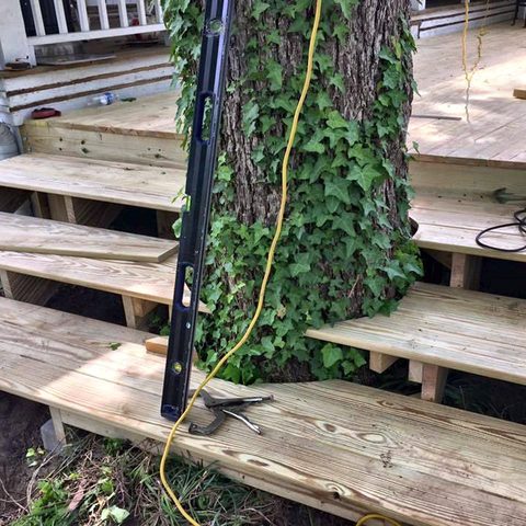 New deck framing and stair stringers built around mature trees on a sloping yard