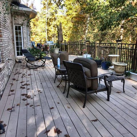 A large deck with outdoor furniture, surrounded by trees in autumn color