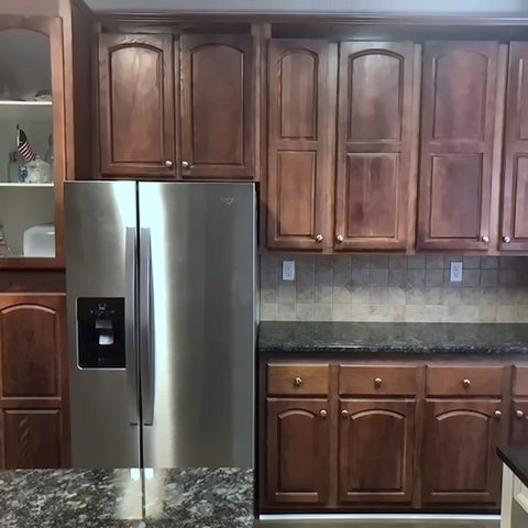 A kitchen before refinishing with dark cherry raised-panel cabinets and a granite counter