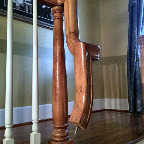 Newel posts and sections of handrail stripped and refinished, standing in a room