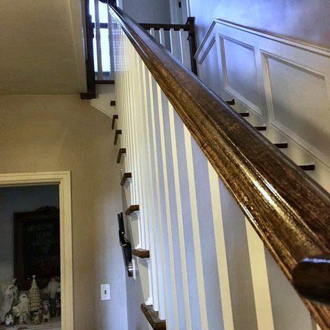 A staircase with a stained handrail, white balusters and painted risers