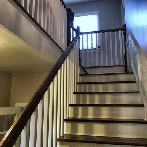 A staircase with stained treads, white risers and a stained handrail