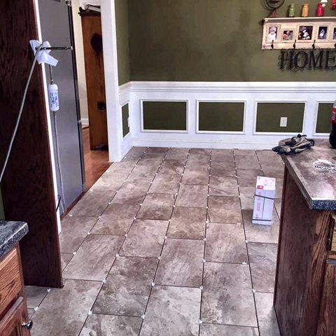 An open-plan kitchen and dining area with a new ceramic tile floor and painted wainscot