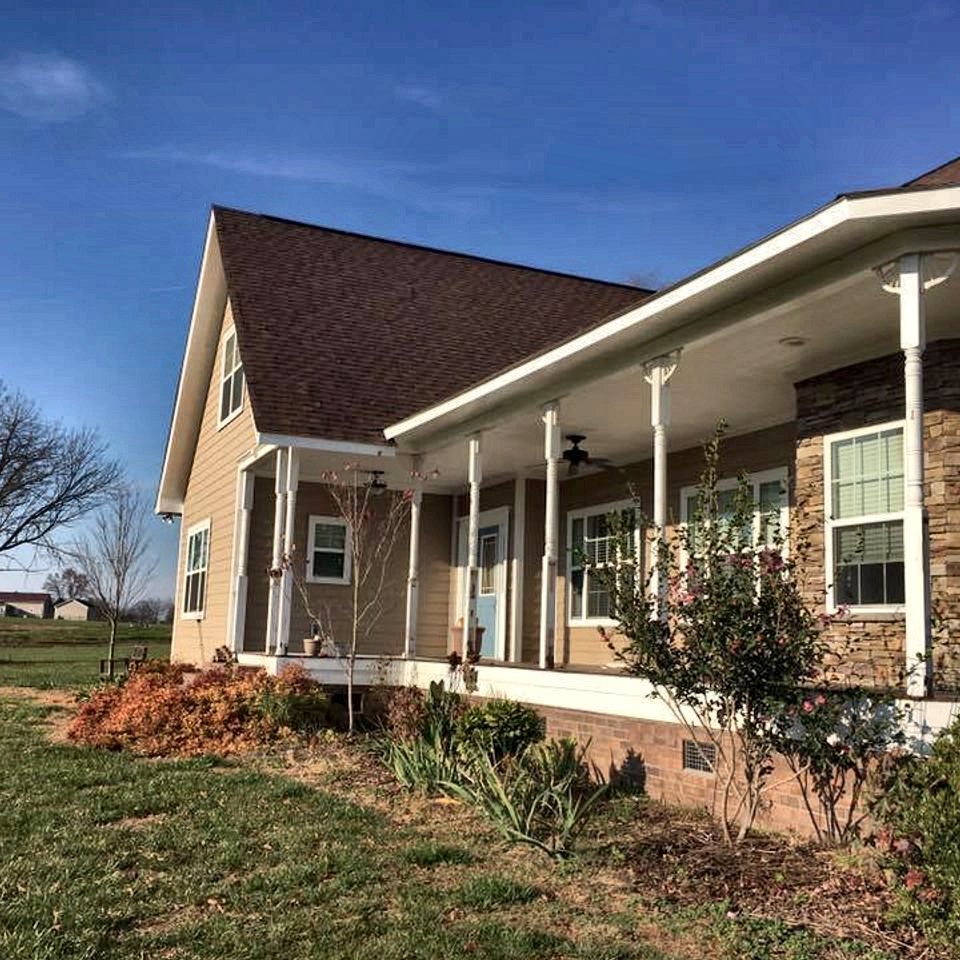 A house with a covered front porch and painted trim in a suburban neighborhood
